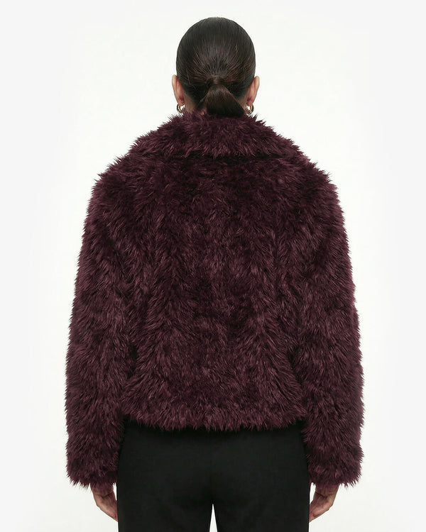Person wearing a dark purple fluffy jacket on a white background - sfosh