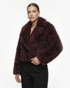Woman wearing a dark purple faux fur jacket on a white background - sfosh