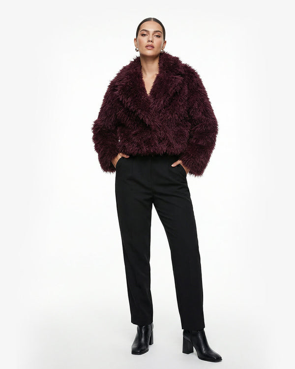 Person wearing a fluffy dark purple jacket and black pants on a white background - sfosh