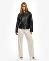 Woman wearing a black leather jacket and white pants on a white backgroundBlack leather jacket on a white background - sfosh