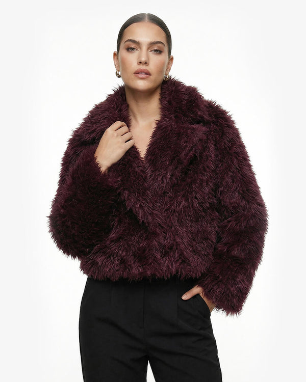 Woman wearing a dark purple fluffy jacket on a white background - sfosh